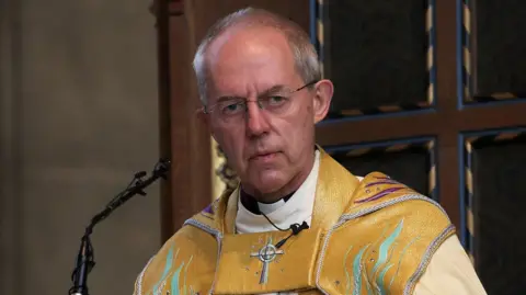 Getty Images Archbishop Justin Welby at a pulpit in yellow robes.