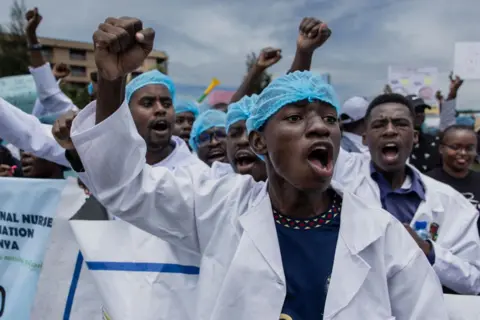 AFP Kenyan doctors chant outside the health ministry headquarters protesting with placards to demand better pay and working conditions in the capital, Nairobi on April 9, 2024.