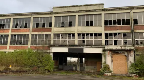 BBC A derelict building frontage with smashed windows and a boarded up doorway