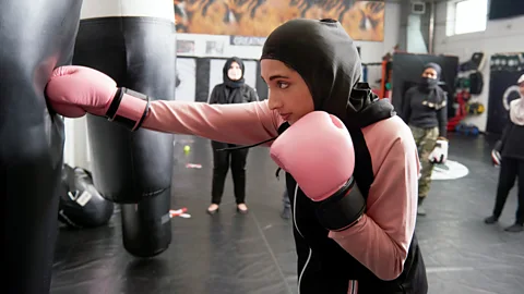 Getty Images Woman with boxing gloves and punching bag