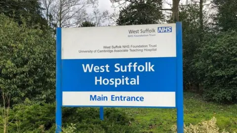 PA Media A sign outside a hospital is blue and white. It has the name of the hospital - West Suffolk Hospital - and the sign says it is the main entrance