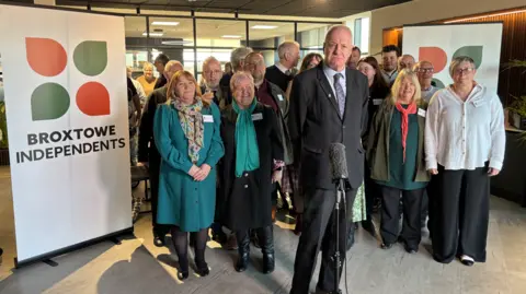 BBC A group of Broxtowe Borough Councillors standing next to a sign that says "Broxtowe Independents"
