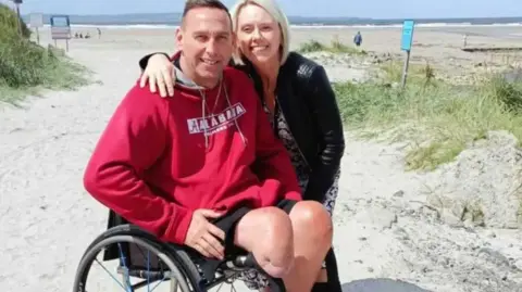Shaun Gash Shaun Gash in a wheelchair on a beach with his wife