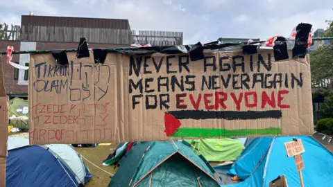 BBC/Ashitha Nagesh Naomi's sign reading 'tzedek, tzedek, tirdof'