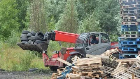 Pacemaker A man driving a telehandler removes tyres from the bonfire on London Road in Belfast