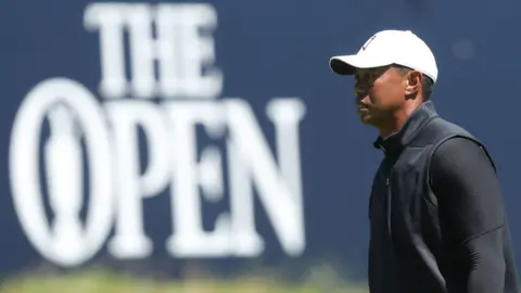 PA Media Tiger Woods walks past a sign at Royal Portrush that reads: The Open