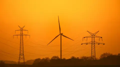 Getty Images Pylons and wind turbine