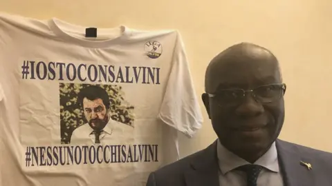 BBC Tony Iwobi standing next to a Salvini t-shirt