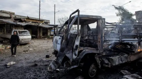 Getty Images A man inspects the damage at the popular market in the city of Ariha after Syrian government airstrikes on the rebel-held Idlib province on 15 Jan