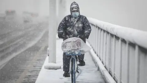 Getty Images A man riding a bike in Wuhan - the epicentre of the coronavirus outbreak in China, 15 February 2020