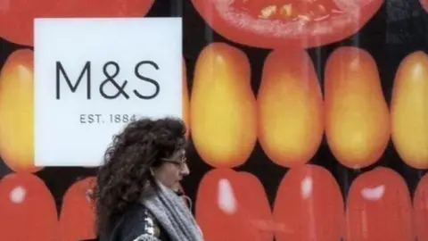 Getty Images Woman walks by M&S storefront