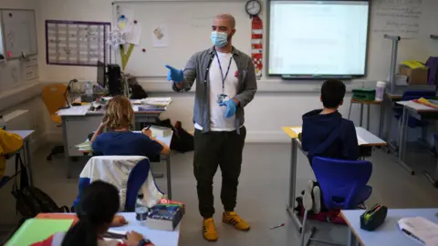 Getty Images A teacher wearing a face mask teaches Year 6 pupils in a classroom with other pupils participating by video conference at the College Francais Bilingue De Londres French-English bilingual school in north London