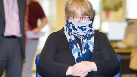 Getty Images Therese Coffey wears a face covering during a visit to a job centre earlier this month