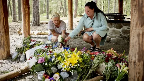 EPA People lay flower bouquets as a makeshift memorial at a forest shelter next to the Haslevej road near Roenne, Bornholm island, Denmark