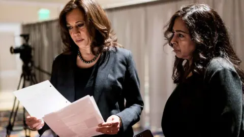 The Washington Post via Getty Images Senator Kamala Harris, with sister and advisor Maya Lakshmi Harris, prepares to speak at a 2019 event