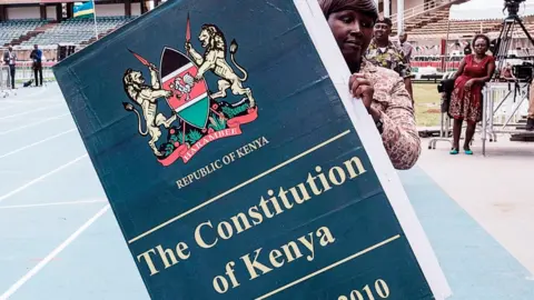 AFP A woman carries a giant replica of the constitution of Kenya ahead of a presidential inauguration ceremony in Nairobi - 17 November 2017