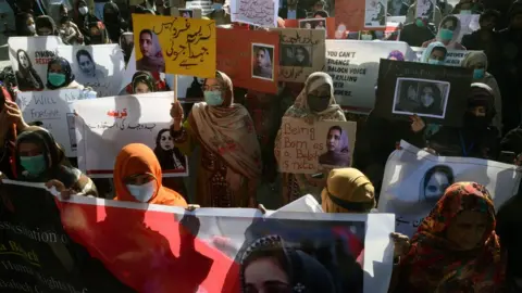 EPA Supporters of Baloch political activist Karima Baloch hold her pictures during a rally to mourn her killing, in Quetta, the provincial capital of Balochistan province, Pakistan, 23 December 2020.