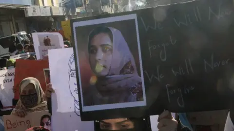EPA Supporters of Baloch political activist Karima Baloch hold her pictures during a rally to mourn her killing, in Quetta, the provincial capital of Balochistan province, Pakistan, 23 December 2020.