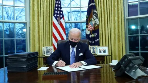 Reuters US President Joe Biden signs documents after being sworn-in
