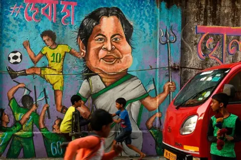 AFP Children play in front of a wall graffiti depicting the Trinamool Congress (TMC) leader and West Bengal state chief minister Mamata Banerjee ahead of the state legislative assembly elections in Kolkata on February 27, 2021.