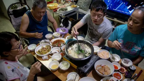 Getty Images A family partakes in a steamboat meal for their reunion dinner at home on the eve of the lunar new year on 11 February 2021 in Singapore.
