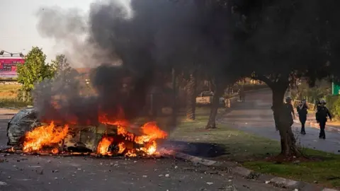 Getty Images An Israeli police car burns after an Arab Israeli demonstration following a funeral in Lod near Tel Aviv