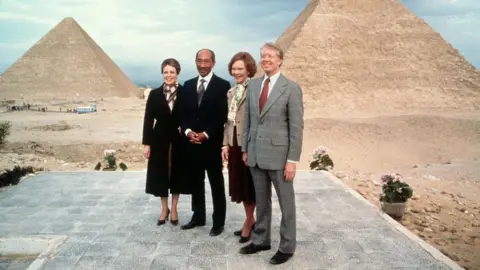 Getty Images Egyptian president Anwar el-Sadat and his wife Jehan pose with President Jimmy Carter and First Lady Rosalynn Carter at the Pyramids, during a diplomatic visit by the Carters on 10 March 1979