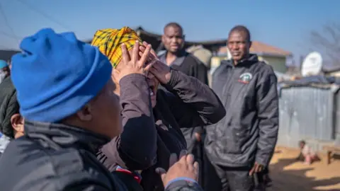 AFP via Getty Images A relative of one of the victims shot dead in a tavern in Soweto reacts next to the crime scene in Soweto