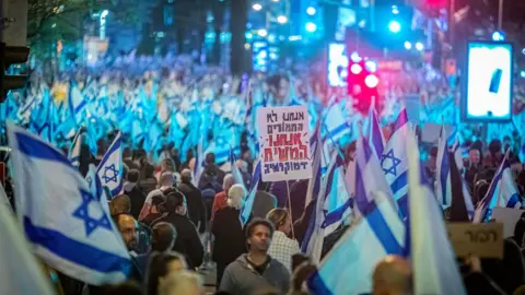 Getty Images A protester holds a placard that says in Hebrew "We are not donkeys we are the Messiah Democracy" during an anti-reform demonstration.