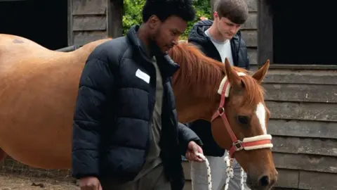 Key4Life Two young men lead a horse