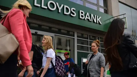 Getty Images People walk past a branch of Lloyds Bank