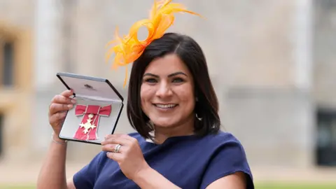 PA Media Camilla Bowry holds her OBE for services to young people, education and the environment