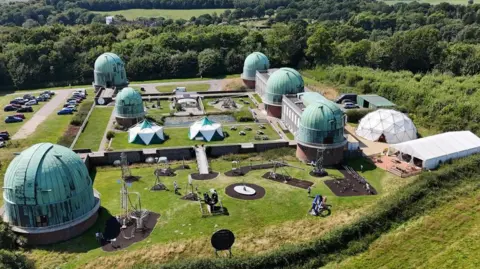 BBC/BEN LEETE A drone image of the Observatory Science Centre at Herstmonceux, showing six green copper domes, with smaller buildings dotted between them.
