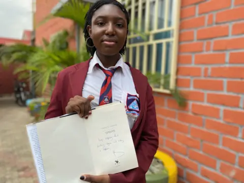 Valeria Offia holds up signed copy of Prince Harry's book Spare
