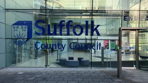 Vikki Irwin/BBC A glass fronted building which is the headquarters of Suffolk County Council. It reads Suffolk County Council in large blue writing