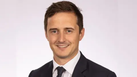 Academy21 Alessandro Capozzi, wearing a dark suit. He has brown hair and has blue eyes.