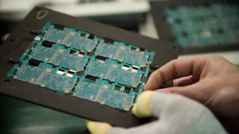 Getty Images Gloved hand holding microchip board