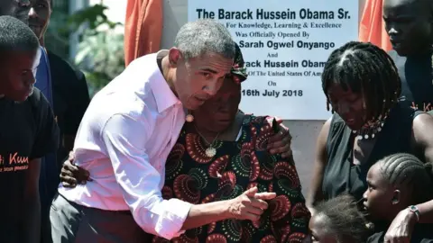 AFP Former US President, Barack Obama (3rdL) with his step-grandmother Sarah (C) and half-sister, Auma (2ndR) and some of the local youth are pictured on July 16, 2018 following the unveiling of a plaque during the opening of the Sauti Kuu Resource Centre, founded by his half-sister, Auma Obama at Kogelo in Siaya county, western Kenya.