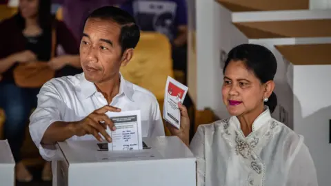 Getty Images Indonesian President Joko Widodo and his wife Iriana vote at a polling station on April 17, 2019 in Jakarta, Indonesia