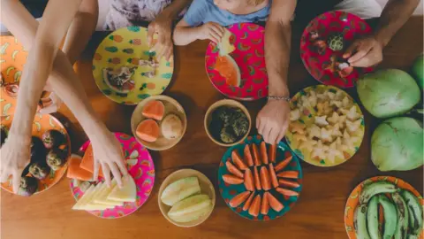 Getty Images People reach for fruit placed on table