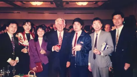 BBC Bob Hawke smiles for a group photo with six Chinese students at a community dinner in Sydney in 1997
