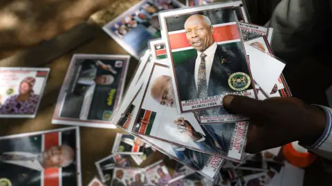 AFP A man sells badges bearing the photo of late former Kenya"s President Daniel Arap Moi, outside Parliament Buildings