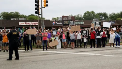 Reuters A mix of protesters and supporters line the road as the motorcade of U.S. President Donald Trump passes by on his way to Kenosha Wisconsin