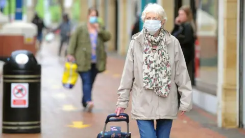 Wales news service Woman wearing a face covering shopping in Caerphilly