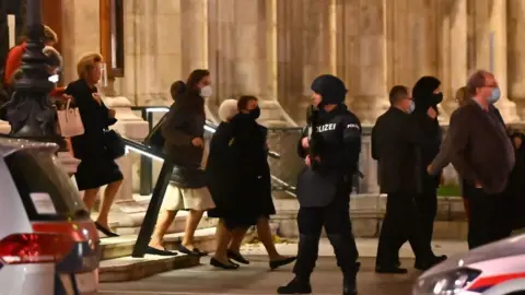 Getty Images Opera guests leave the state opera under the supervision of armed policemen, in the centre of Vienna on November 2, 2020