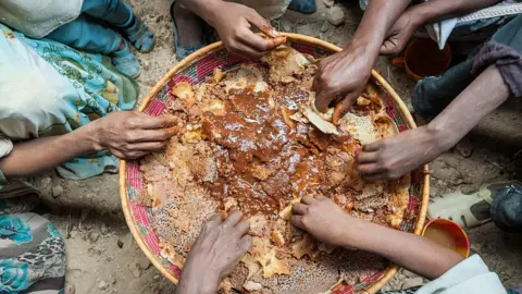 Getty Images Hands of people sharing a traditional dish (archive)