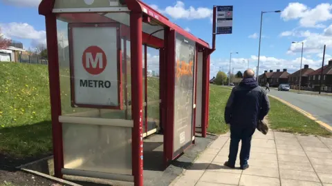BBC William Thomas stands next to a bus stop