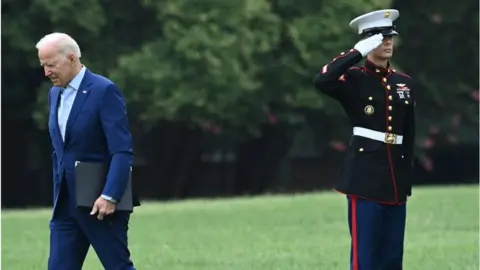 Getty Images Biden walks past a Marine at the White House