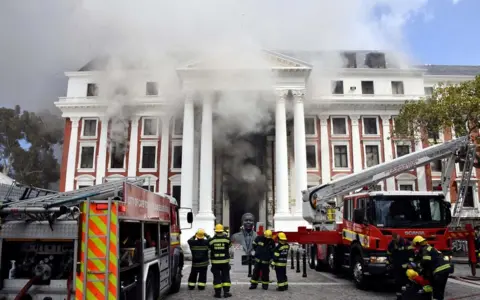Reuters Firefighters work after a fire broke out in the Parliament in Cape Town, South Africa, January 2, 2022
