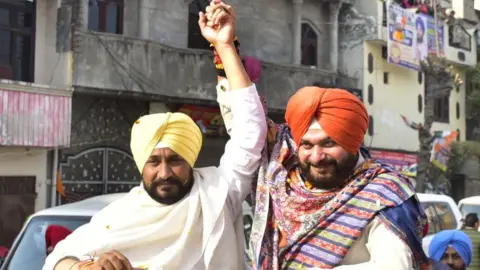 Getty Images Punjab Chief Minister Charanjit Singh Channi with Punjab Congress President and candidate from Amritsar East Constituency Navjot Singh Sidhu during a road show campaign ahead of Punjab assembly election on February 17, 2022 in Amritsar, India.